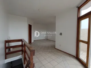 Hall de entrada com piso de cerâmica e corrimão de madeira.
