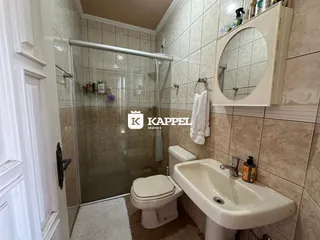 Banheiro com box de vidro, vaso sanitário e pia.