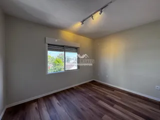 Sala de estar com piso de madeira e grande janela.