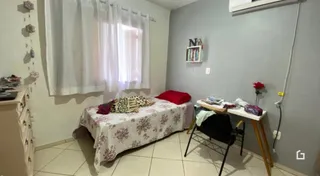 Quarto com cama e cortinas brancas em ambiente claro.
