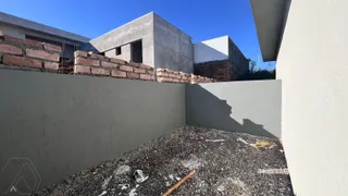 Fachada de uma construção em andamento com paredes de concreto e tijolos aparentes.