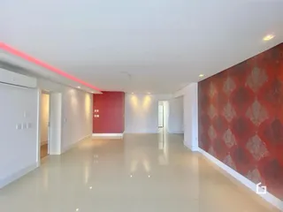 Corredor interno de uma residência com paredes brancas e uma parede de destaque vermelha.