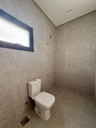Foto interna de um banheiro com piso de cerâmica e vaso sanitário branco.