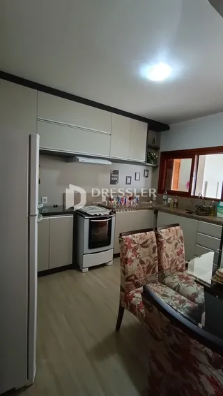 Interior de uma sala de estar com cozinha em um imóvel no Brasil.