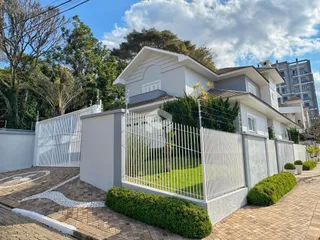 Fachada de uma residência em Lajeado, Brasil, com muro e portão branco.
