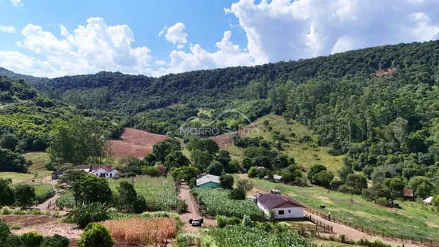 Vista panorâmica de uma propriedade rural com colinas verdes e vegetação densa.