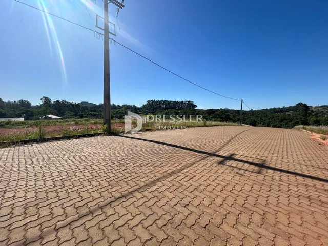Área externa pavimentada com sombra de uma poste.
