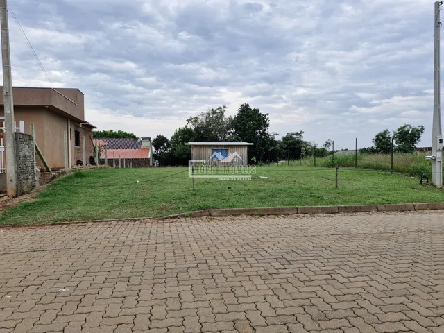 Vista externa de um terreno gramado com árvores ao fundo.
