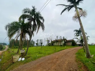 Vista da propriedade rural em Lajeado, Brasil, com estrada de terra e vegetação.