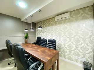 Sala de jantar com mesa de madeira e cadeiras de couro pretas.