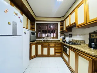Cozinha com armários de madeira e piso cerâmico claro.