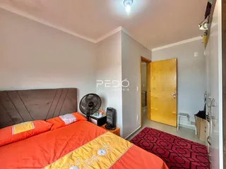 Quarto com cama de casal e roupa de cama laranja.