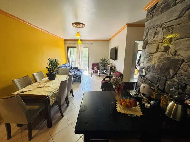 Interior de uma sala de jantar com paredes amarelas e uma parede de pedra.