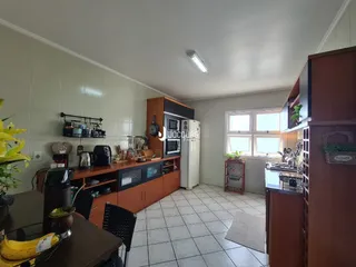 Foto interna de uma cozinha com armários e piso cerâmico.