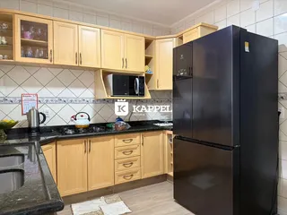 Foto de uma cozinha com armários de madeira clara e eletrodomésticos pretos.
