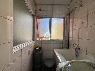 Foto interna de um banheiro com revestimento de azulejos claros.