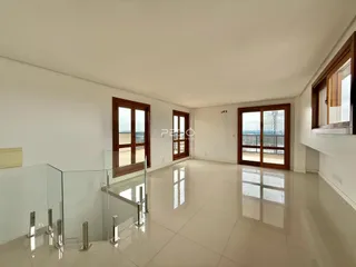 Interior de uma sala de estar ampla com piso de porcelanato claro e divisória de vidro.