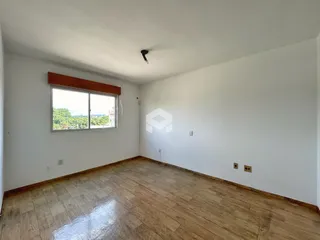 Ambiente interno de uma sala com piso de madeira e janela.