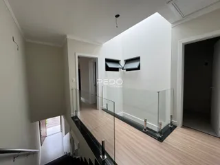 Hall de entrada com piso de madeira e guarda-corpo de vidro.
