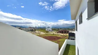 Vista externa de uma residência branca com paisagem ao fundo.