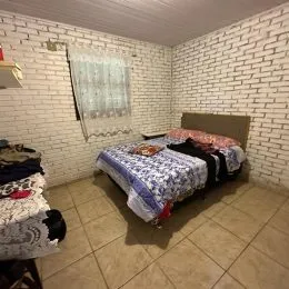 Quarto com paredes de tijolos brancos e cama coberta.