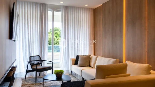 Sala de estar com cortinas brancas e sofá claro.