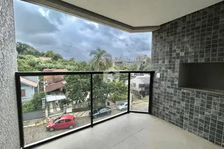 Vista da rua e casas de Lajeado, Brasil, através de uma varanda com grade de vidro.