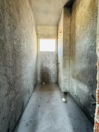 Corredor interno de uma residência com paredes de concreto aparente.