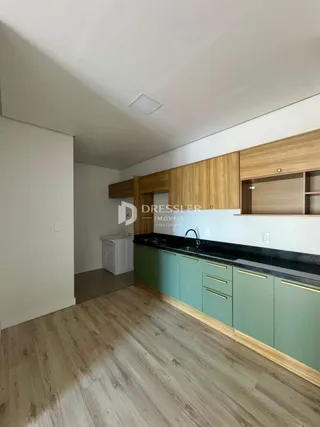Ambiente interno com piso de madeira e armários de cozinha.