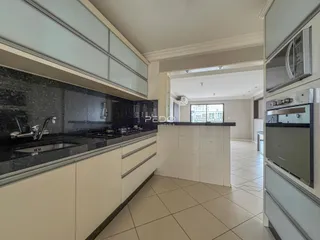 Cozinha moderna com armários brancos e bancadas escuras.