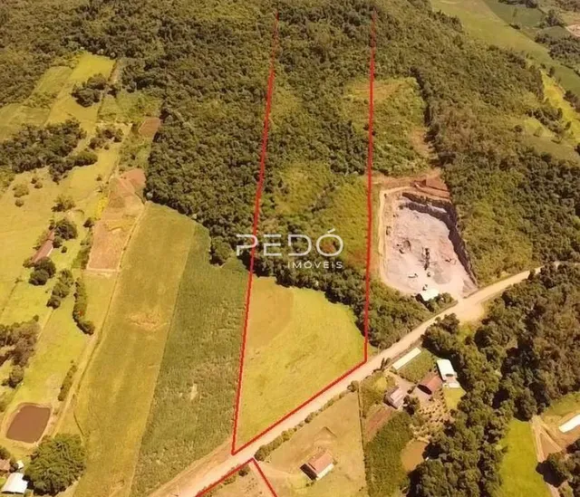 Vista aérea de uma propriedade rural com vegetação e áreas de terra exposta.