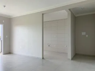 Ambiente interno com paredes brancas e piso claro em uma área comum.