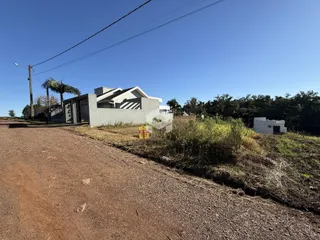 Vista da fachada de uma casa em uma área rural com estrada de terra.