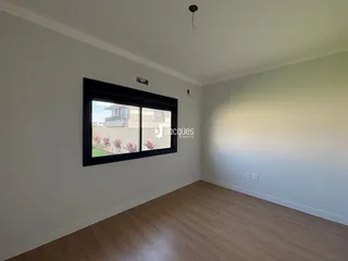 Sala de estar com piso de madeira clara e janela.