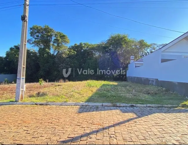 Fachada de uma propriedade com gramado e árvores ao fundo.
