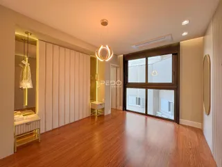 Sala de estar com piso de madeira polida e grandes janelas.