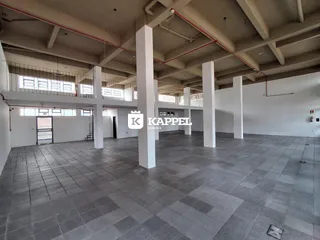 Vista interna de um grande hall com colunas e piso de cerâmica.