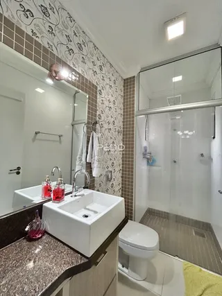 Banheiro com azulejos decorativos e bancadas de granito.