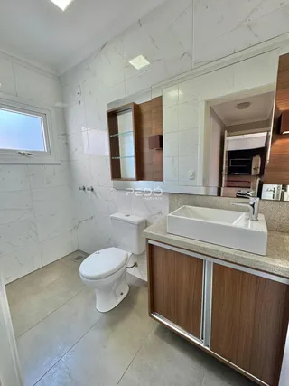 Banheiro moderno com revestimento em mármore branco e armários de madeira.