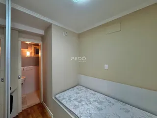 Foto de um quarto com paredes bege e acesso a um banheiro.