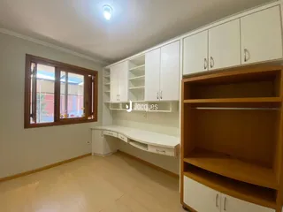 Uma sala com armários brancos e madeira clara na residência.