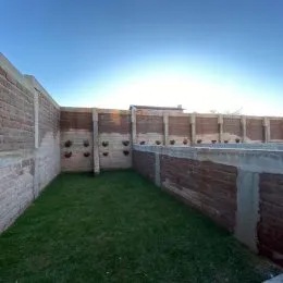 Vista externa de um jardim com muro de tijolos.