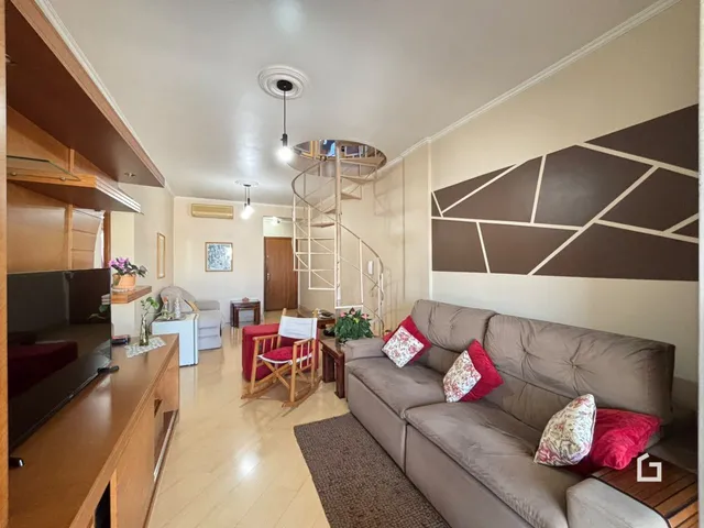 Sala de estar com piso de madeira e escadaria em um apartamento em Lajeado.