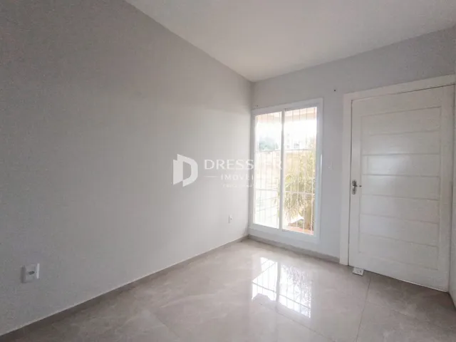 Interior de uma sala com paredes brancas e piso de cerâmica clara.