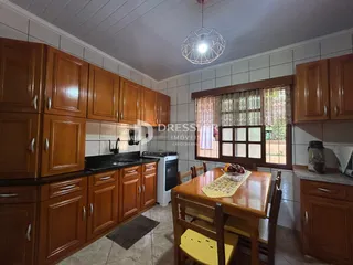 Interior de uma cozinha com armários de madeira e mesa de jantar em Lajeado.