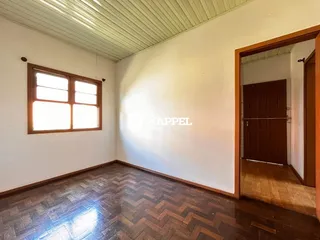 Sala com piso de madeira escura e janela na parede.