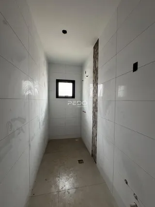Corredor interno com paredes brancas e piso claro.