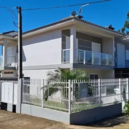 Foto da fachada de uma casa em Lajeado, Brasil, com varanda e cerca branca.