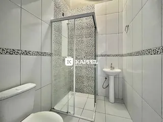 Banheiro com box de vidro e revestimento de azulejos brancos.