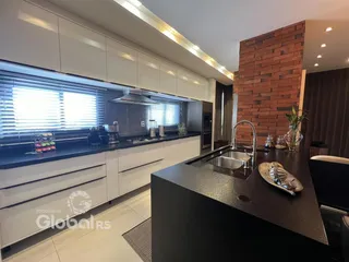 Cozinha moderna com armários brancos e bancadas escuras.